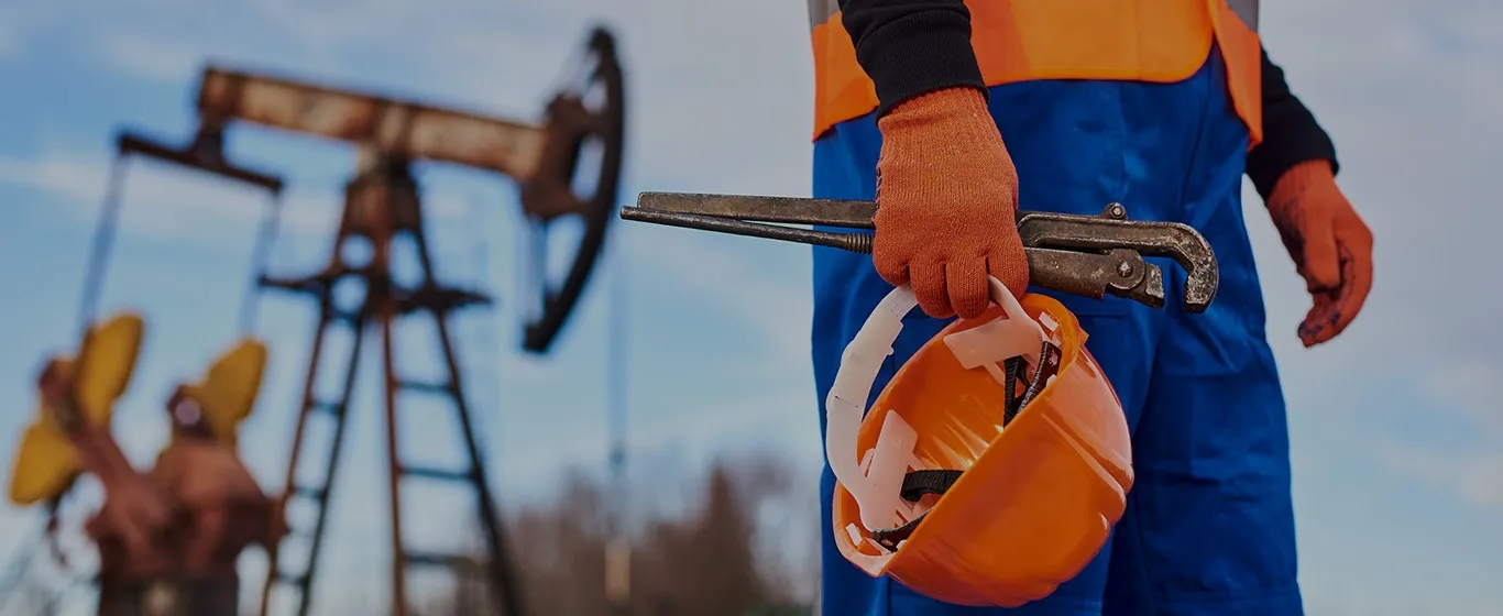 Ouvrier pétrolier tenant un casque de chantier et une clé serre-tube
