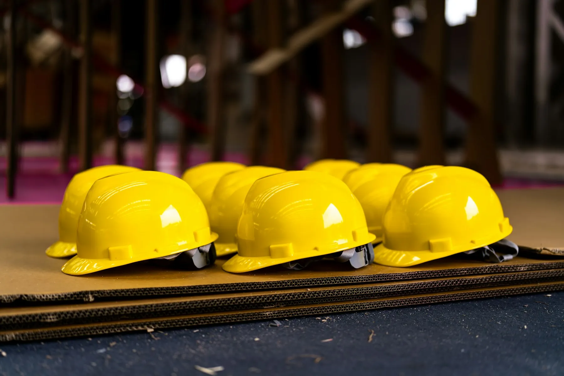 Rows of yellow hard hats laid out on cardboard sheets